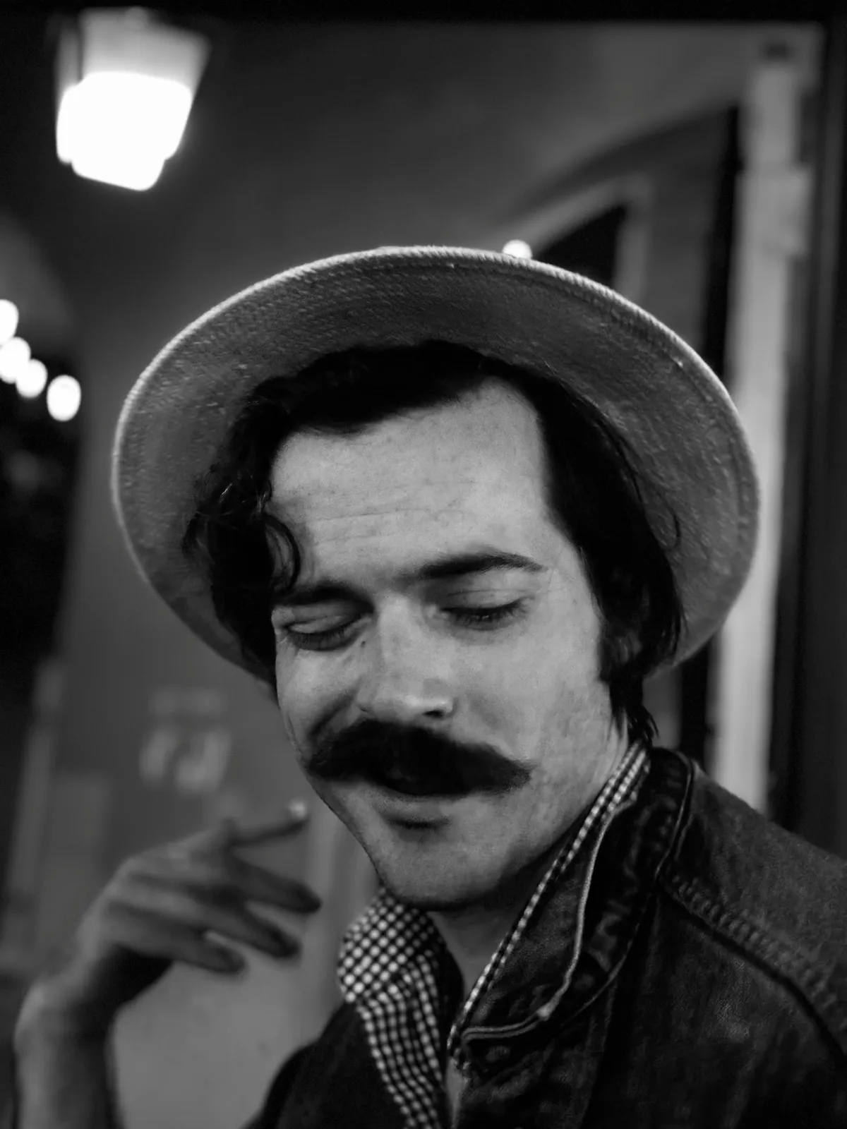 Untitled (Lamplight), black and white photograph by Mathieu: a portrait in a hat under lamplight