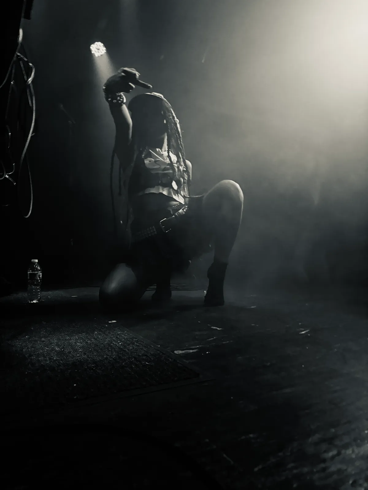 Untitled (Spotlight), black and white photograph by Mathieu: a performer kneeling in a spotlight