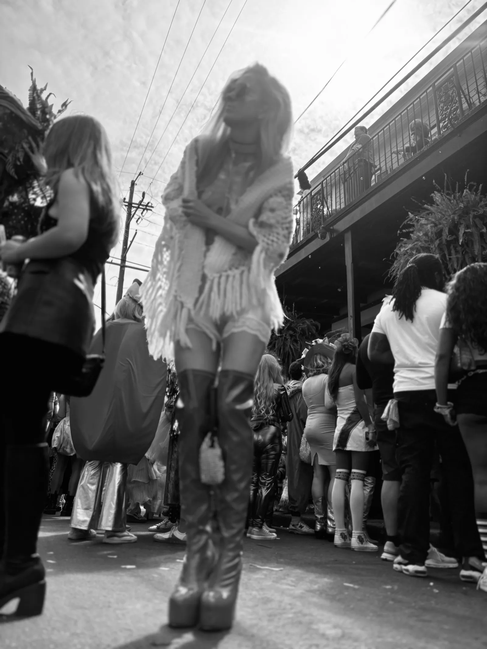Untitled (Parade), black and white photograph by Mathieu: a costumed crowd filling a street beneath a balcony