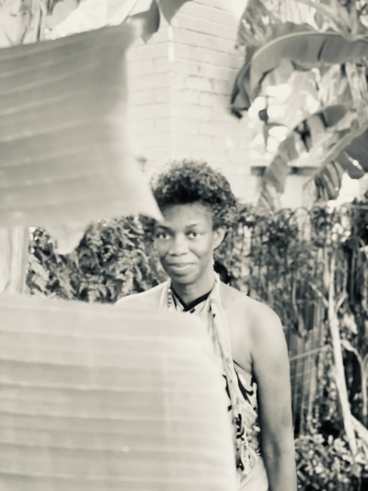 Untitled (Leaves), black and white photograph by Mathieu: a woman glimpsed between banana leaves in bright light