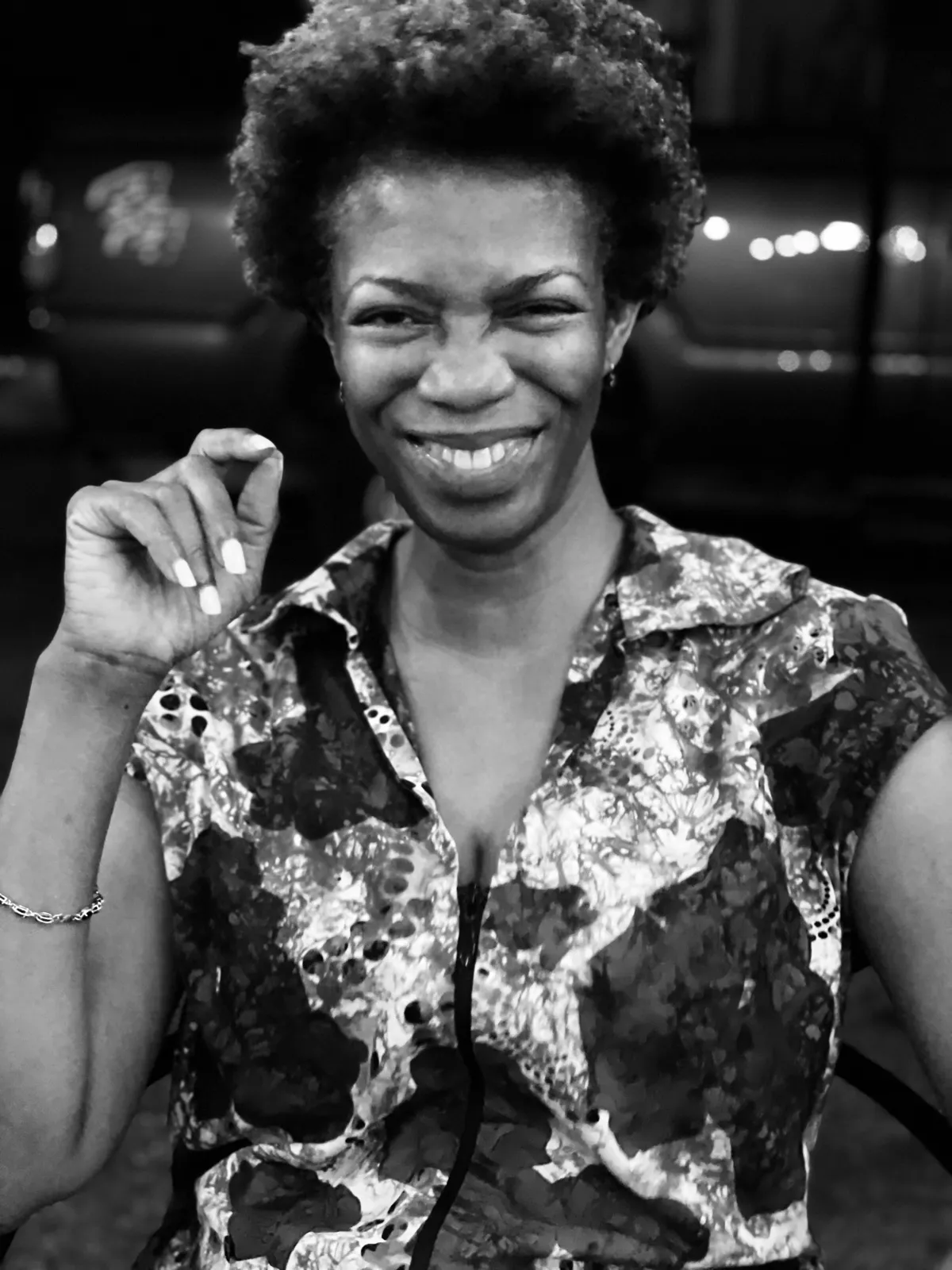 Untitled (The Smile), black and white photograph by Mathieu: a woman smiling at night in a patterned shirt