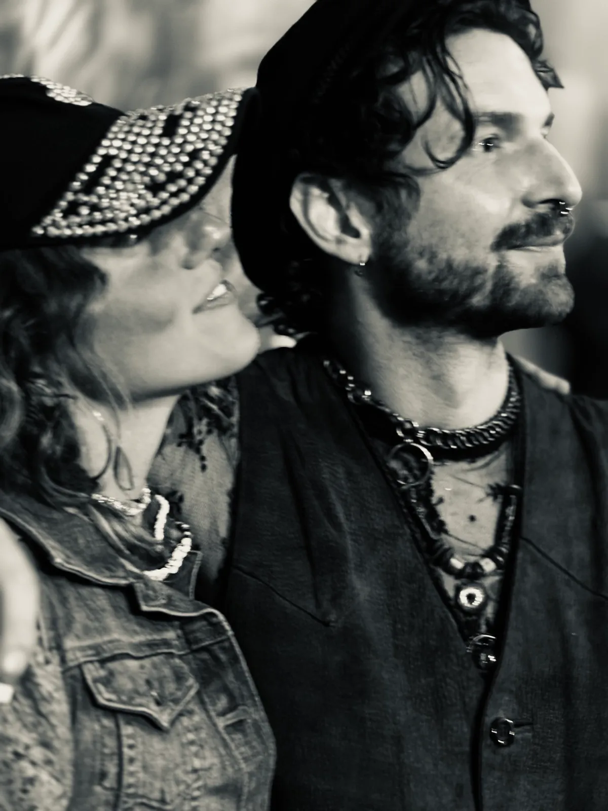 Untitled (Two Hats), black and white photograph by Mathieu: a couple in studded caps looking away together