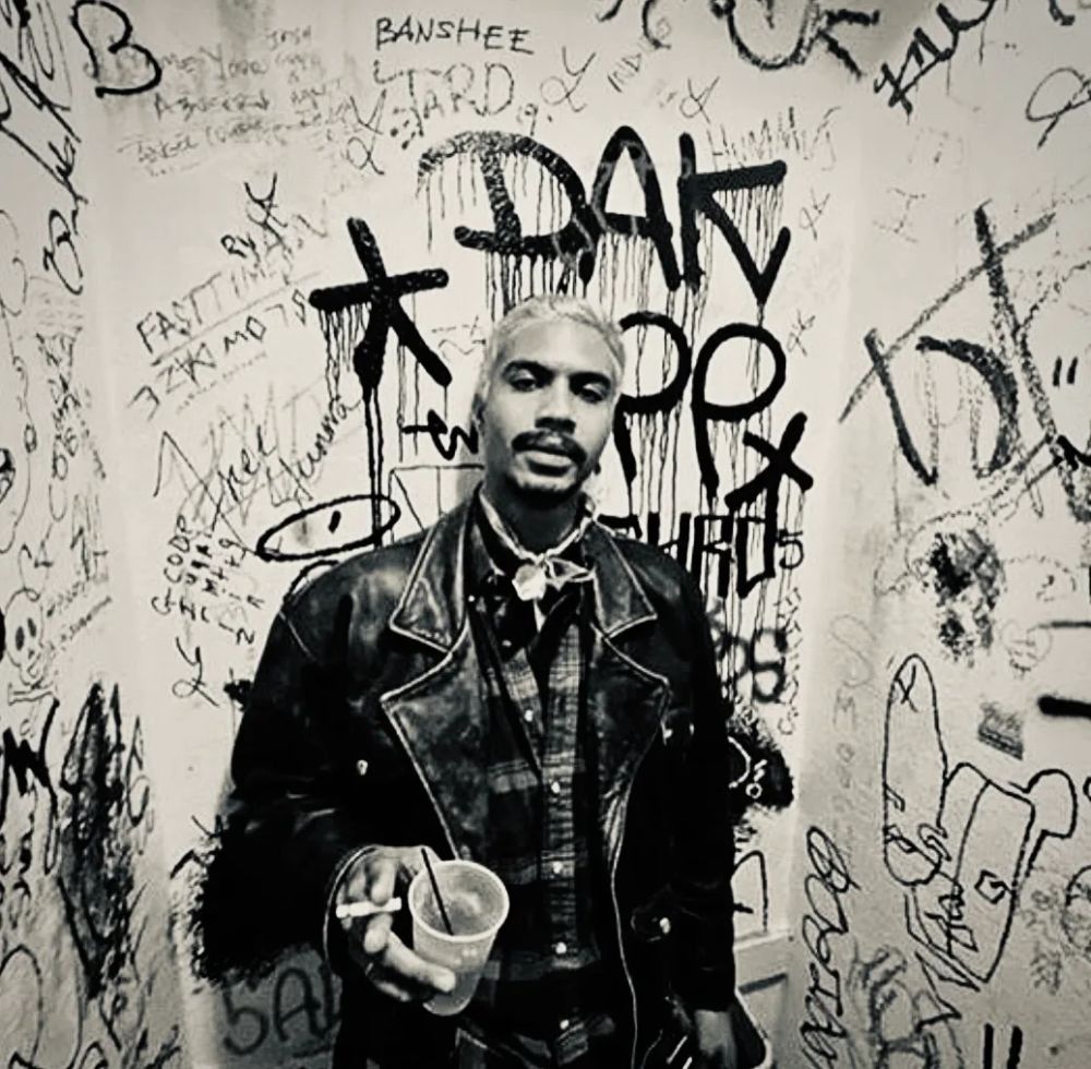 Portrait of Mathieu against a graffiti-covered wall